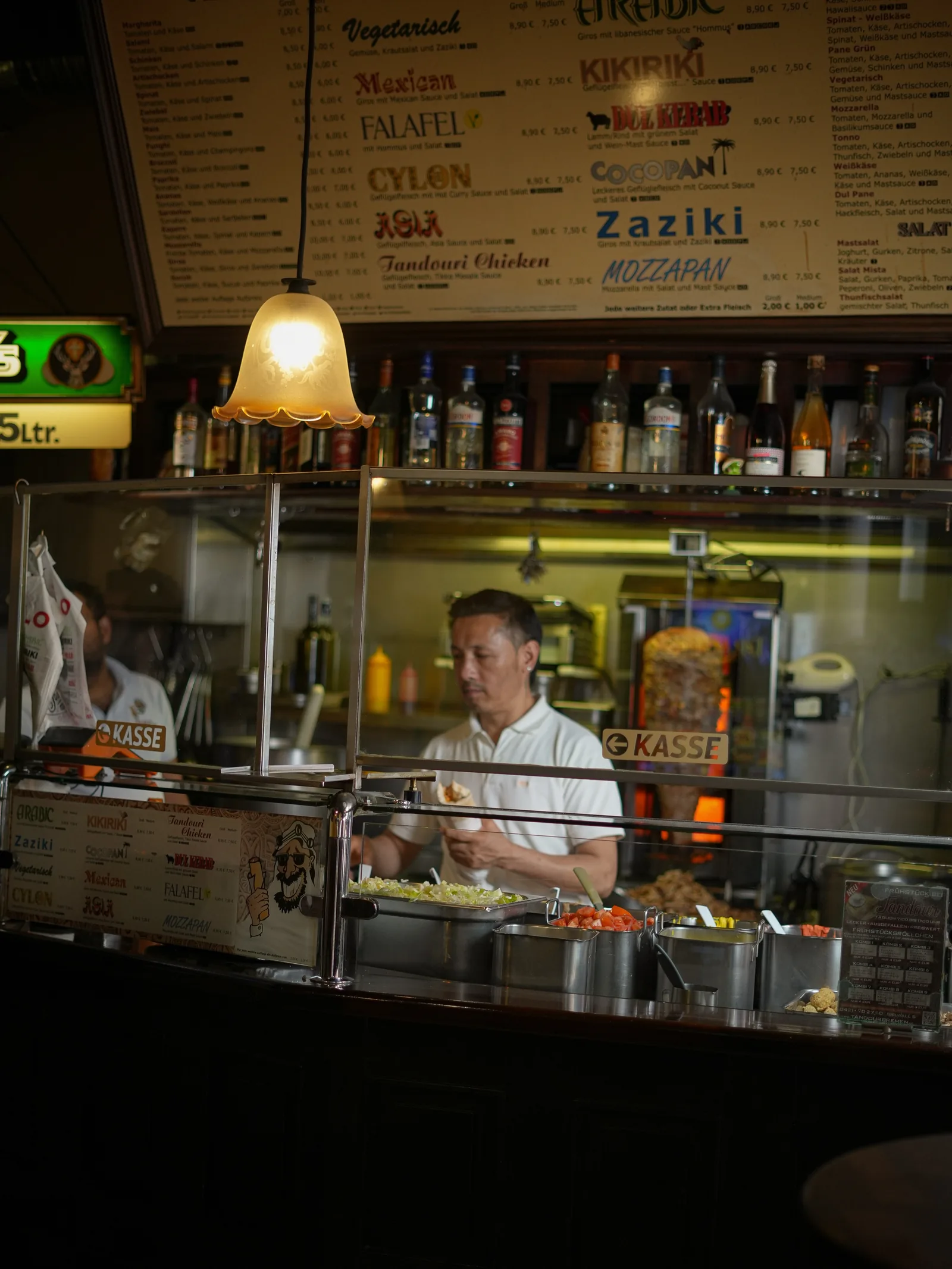 Die Theke am Sielwall 5: Zutatenbehälter, dahinter der Spieß, darüber die Tafel mit den zwölf Rollo-Sorten
